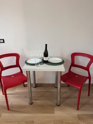 A dining table with two red chairs, a bottle of wine, and two empty plates.