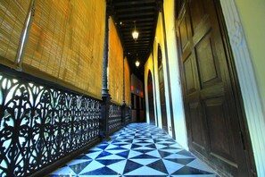 A corridor with a black and white checkered floor, ornate black metal railings, and wooden doors. - Deewanji Ni Haveli (Ahmedabad)