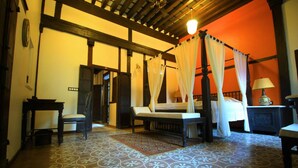 Una habitación tradicional con una cama con dosel, un banco de madera y una pequeña mesa.