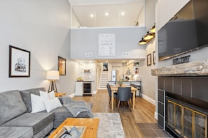 Een moderne woonkamer met een grijze bank, een salontafel en een open haard.