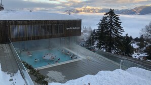 Zona de spa con piscina y vistas a montañas nevadas.