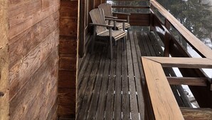 Terraza de madera con sillas Adirondack y barandilla de madera.