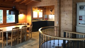 Interior de madera con comedor, cocina y escalera.