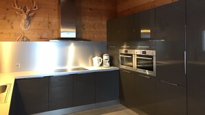 Una cocina moderna con electrodomésticos de acero inoxidable, vigas de techo de madera y una cabeza de venado montada en la pared.
