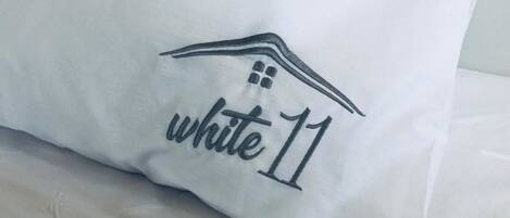 Almofada com um desenho de casa e a inscrição "white 11" bordada.