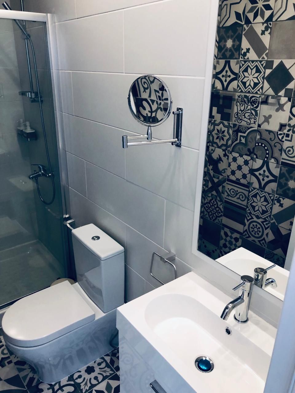 Un baño con ducha, inodoro, lavabo y espejo.