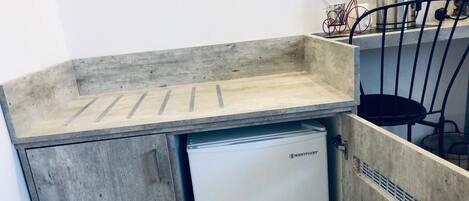 Una kitchenette compacta con un mini refrigerador integrado, un lavamanos y una pequeña encimera.