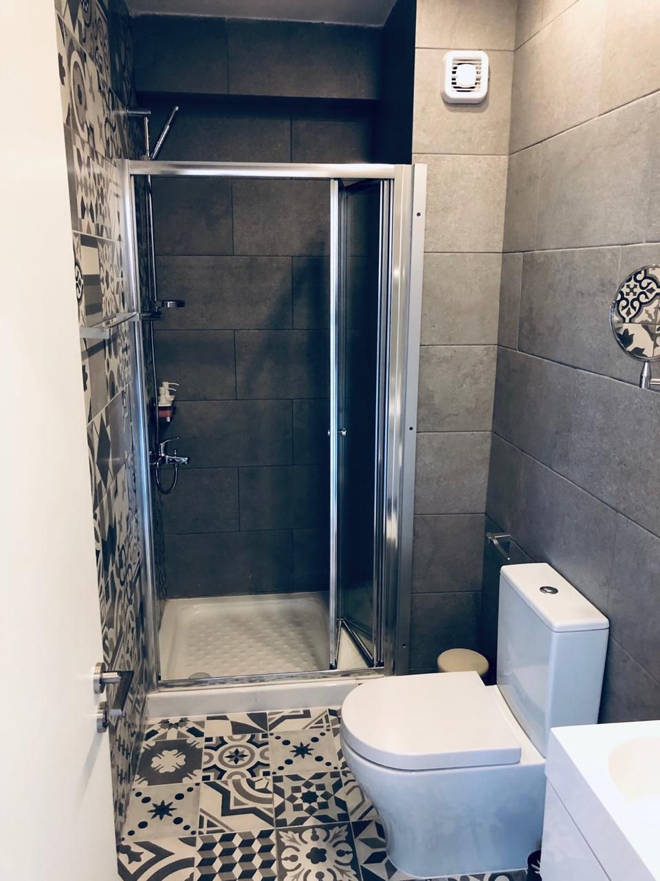 A bathroom with a shower, toilet, and sink.