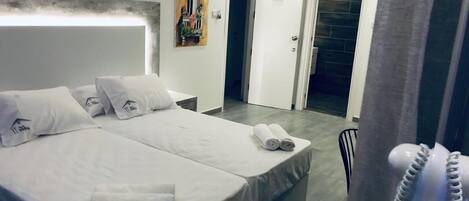 A hotel room with a large bed, a bedside table, a phone, and a painting on the wall.