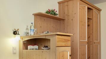 Een slaapkamer met een houten bed, een klein bureau met een lamp en een kledingkast.
