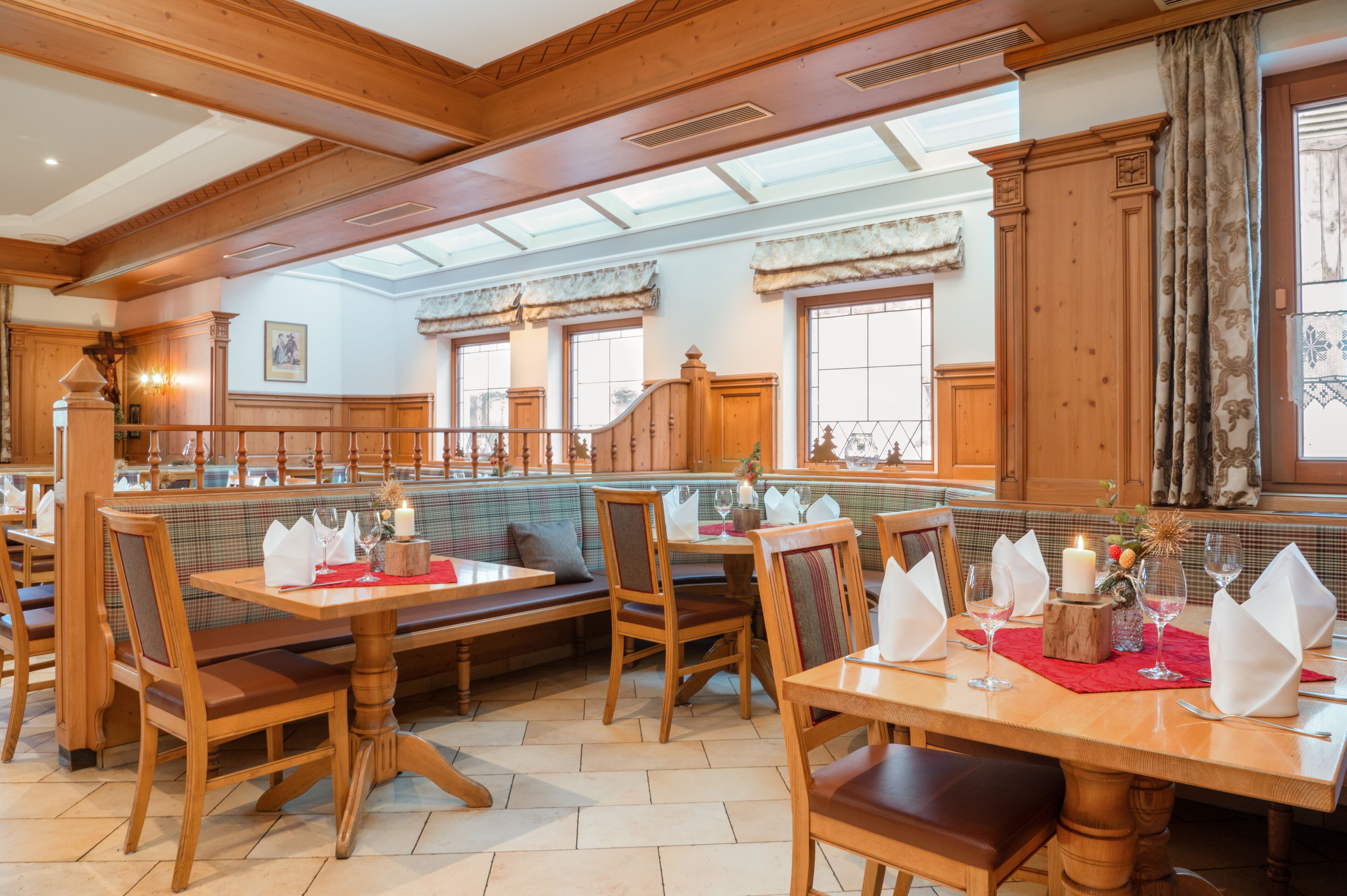 A restaurant with wooden furniture, a high ceiling, and large windows.