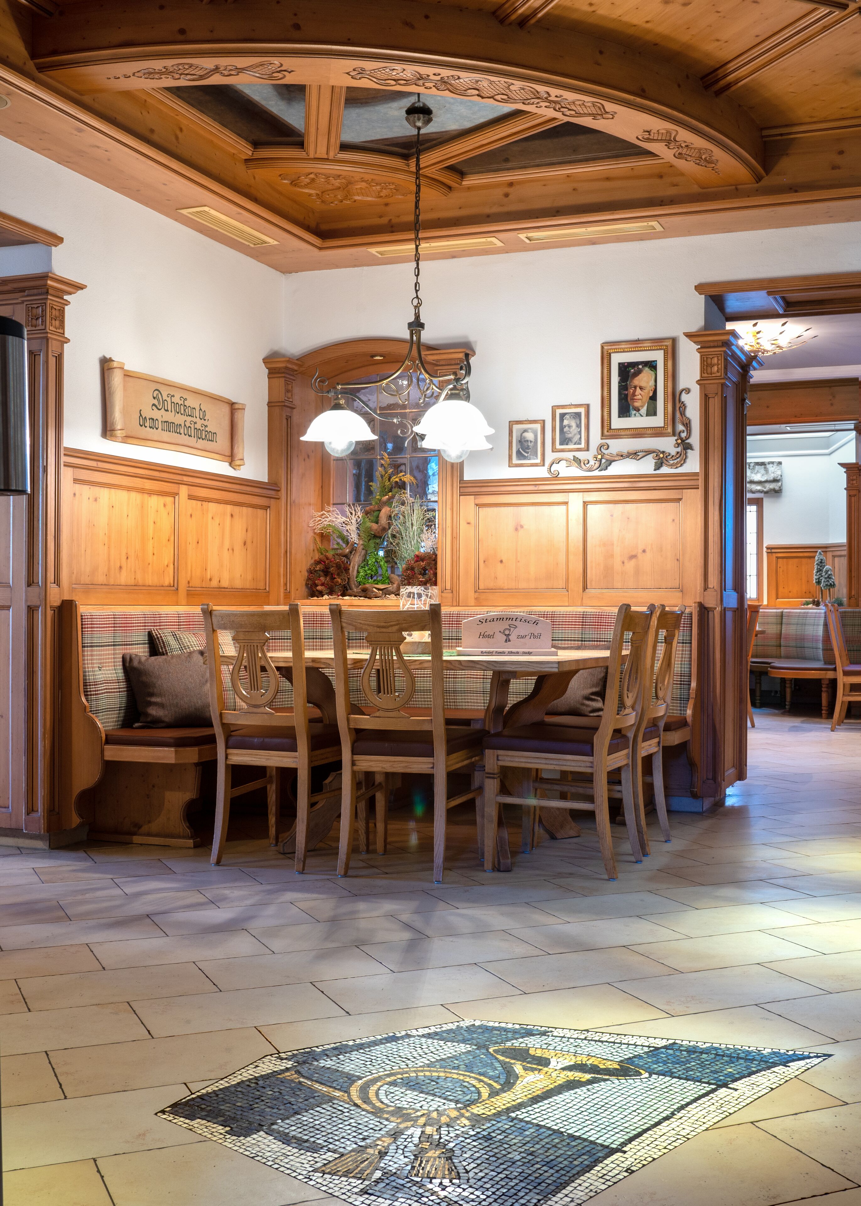 A wooden dining area with a chandelier, wooden cabinets, and a tiled floor.