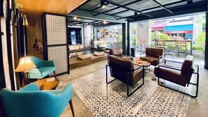 A modern interior with a wooden ceiling, a patterned rug, and seating areas with leather sofas and armchairs. - BE Rendez Vous Hotel (Patong)