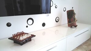 Un mueble multimedia blanco con un tablero de ajedrez, un televisor y elementos decorativos.