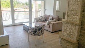 Una sala de estar con un sofá beige, un sillón floral y una pared de piedra.