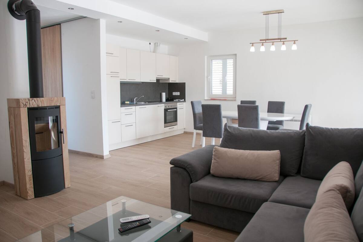 A modern living room with a grey sofa, a glass coffee table, and a fireplace.