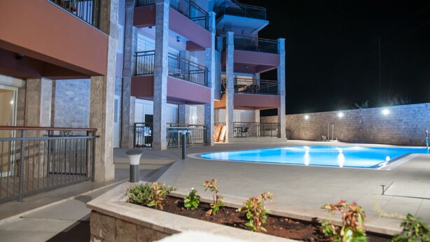 Un hotel de varios pisos con piscina, zona de estar al aire libre y un balcón bien iluminado.
