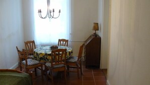 Un coin repas avec une table ronde, six chaises en bois, un lustre et une lampe posée sur un meuble.