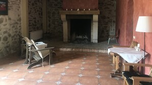 Una habitación rústica con pared de piedra, chimenea y suelo de baldosas.