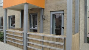 Um edifício moderno com fachada de tijolos, janelas amplas e cerca de madeira.