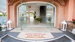 A hotel entrance with a glass door, a brick archway, and a welcome mat. - Masseria Nobile (Fisciano)