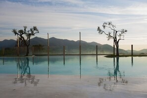 Een seizoensgebonden buitenzwembad, een infinitypool en ligstoelen