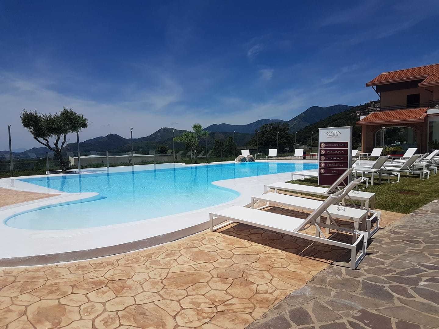 A swimming pool with lounge chairs, a stone patio, and a mountain backdrop.