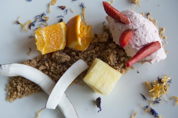 Un plato de postre con distintos ingredientes, como una rodaja de naranja, una bola de helado y un trozo de pastel.
