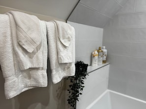 A bathroom with white towels hanging on a rack, a plant, and toiletries on a shelf. - Water Hill Gem - Walk to Downtown - Backyard Oasis (Ann Arbor)