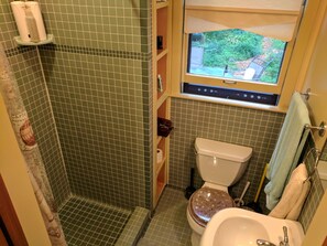 A small bathroom with a toilet, sink, and a window with a view of greenery. - Water Hill Gem - Walk to Downtown - Backyard Oasis (Ann Arbor)