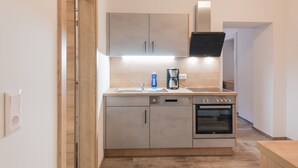 A modern kitchen with a built-in oven, a coffee maker, and a dishwasher. - Appartementhaus Hohe Tauern (Obervellach)
