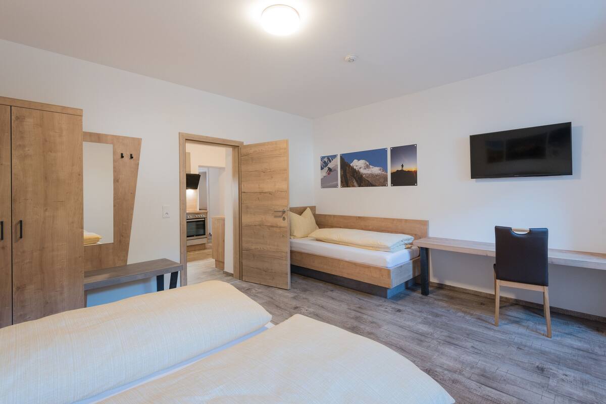 Um quarto moderno com uma cama, uma escrivaninha e uma televisão.