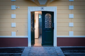 Entrada de un edificio con puerta verde, número 18, y una reja decorativa de metal.