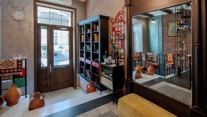 A room with a wooden door, a bookshelf, a mirror, and a yellow bench. - Wine Story Hotel  (Tbilisi)