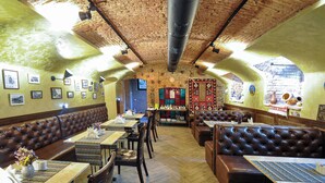 A restaurant with wooden walls, leather booths, and tables with patterned tablecloths. - Wine Story Hotel  (Tbilisi)