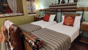 A traditional room with a bed, a bench, and a window with curtains. - Wine Story Hotel  (Tbilisi)