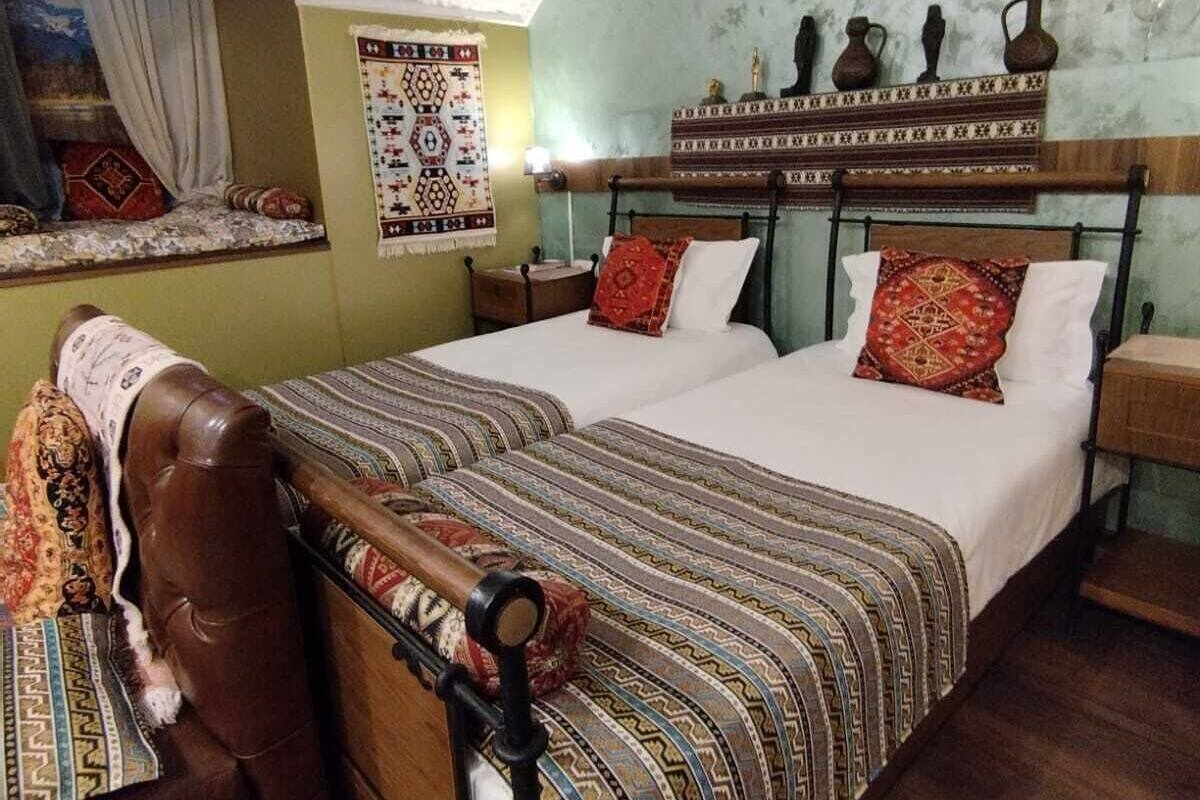 A traditional room with a bed, a bench, and a window with curtains.