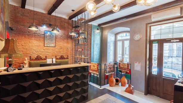 A restaurant interior with exposed brick walls, a wooden ceiling, and a bar area with stools. - Wine Story Hotel  (Tbilisi)