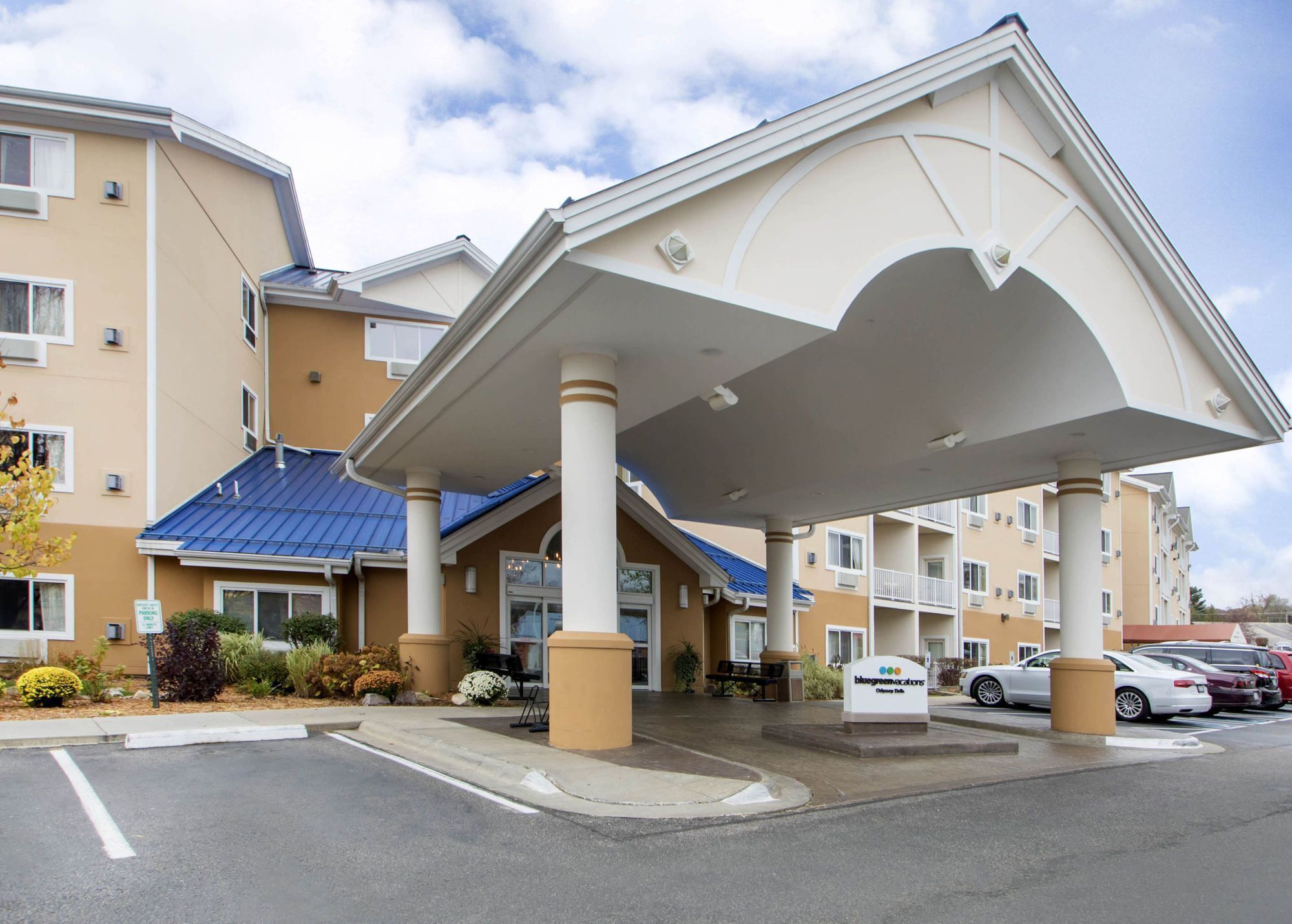 A hotel with a covered entrance, multiple floors, and a parking lot.