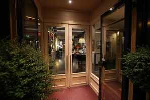 A corridor with glass doors leading to a room with a piano.