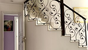 A curved staircase with ornate black railings, a white door, and a potted plant. - Super central and comfortable house in historic 19th-century building. (Acireale)