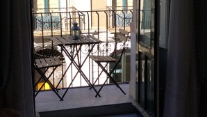 A balcony with a table and chairs, a hanging lantern, and a view of buildings in the background. - Super central and comfortable house in historic 19th-century building. (Acireale)