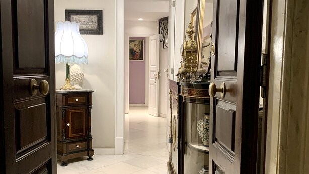 A hallway with dark wooden doors, a chandelier, a lamp, and a cabinet with decorative items. - Super central and comfortable house in historic 19th-century building. (Acireale)