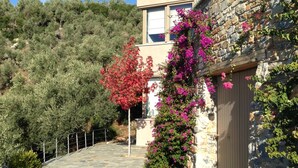 Un sendero de piedra que lleva a un edificio de piedra con una puerta de madera y flores rosas.