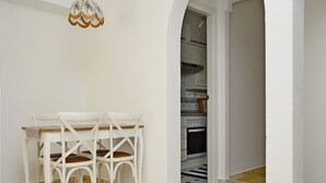 Een eethoek met een tafel en stoelen, een kroonluchter en uitzicht op een keuken.