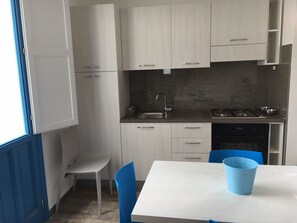 Efficient kitchen with stove, light-colored cabinets, and a small dining area.
