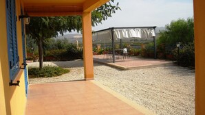 Un espacio cubierto con mobiliario exterior y vistas a un edificio al fondo.
