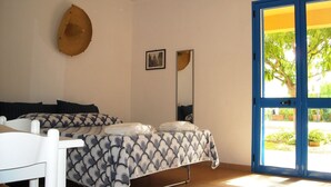 Un dormitorio con cama, una silla, un espejo y una puerta que da a un espacio exterior.