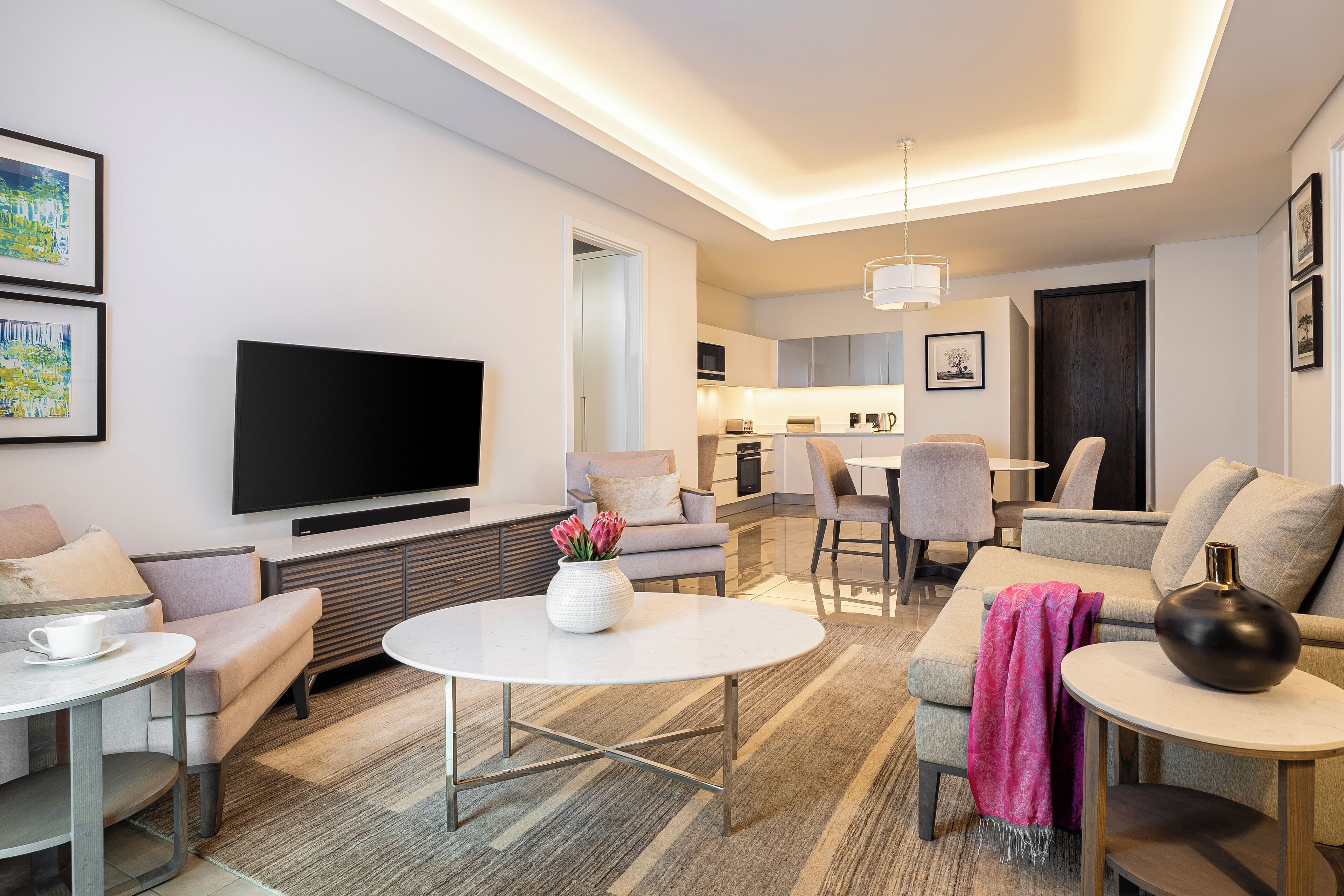 A modern living room with a flat-screen TV, a round coffee table, and a sofa.