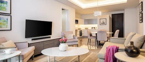 A modern living room with a flat-screen TV, a round coffee table, and a sofa.